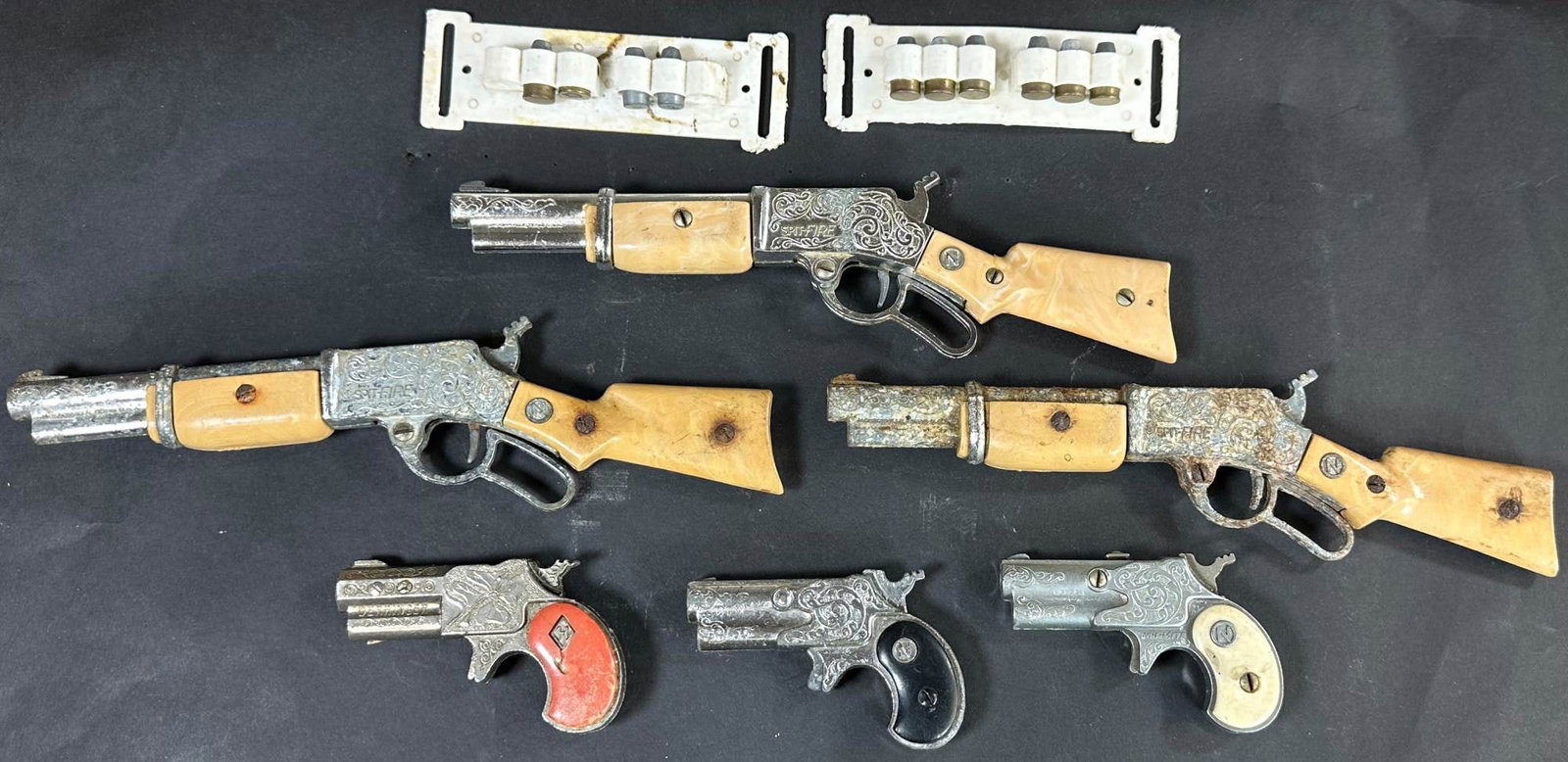 GROUPING OF SIX CAP GUNS W/ TWO BULLET HOLDERS: 345. GROUPING OF SIX CAP GUNS W/ TWO BULLET HOLDERS | Includes three Spitfires, a Derringer and two Dyna-Mite guns with two bullet holders. | 9" l. | Some corrosion to one rifle, overall (Very Good Co