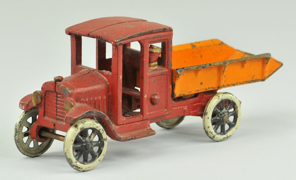 FREIDAG DUMP TRUCK: c. 1920's, scarce example, cast iron, painted in red cab with cast in driver and orange tilt body with tension spring at base, spoke wheels. 8 3/8" l.