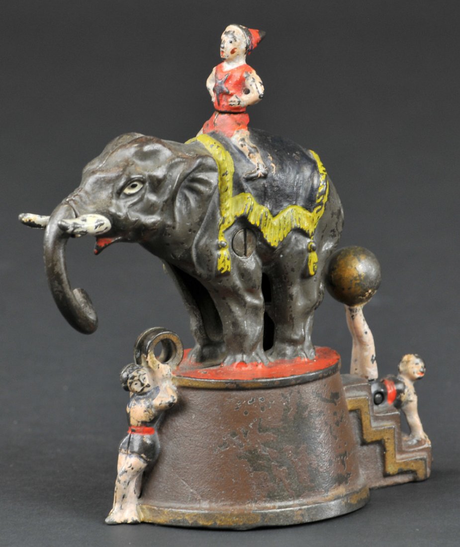 ELEPHANT & THREE CLOWNS MECHANICAL BANK: Tan base, J & E Stevens Co., designed by James H. Bowen, patented 8/28/1883. Place the coin between the rings held by the acrobat. Move the ball on the feet of the other acrobat, and the elephant will