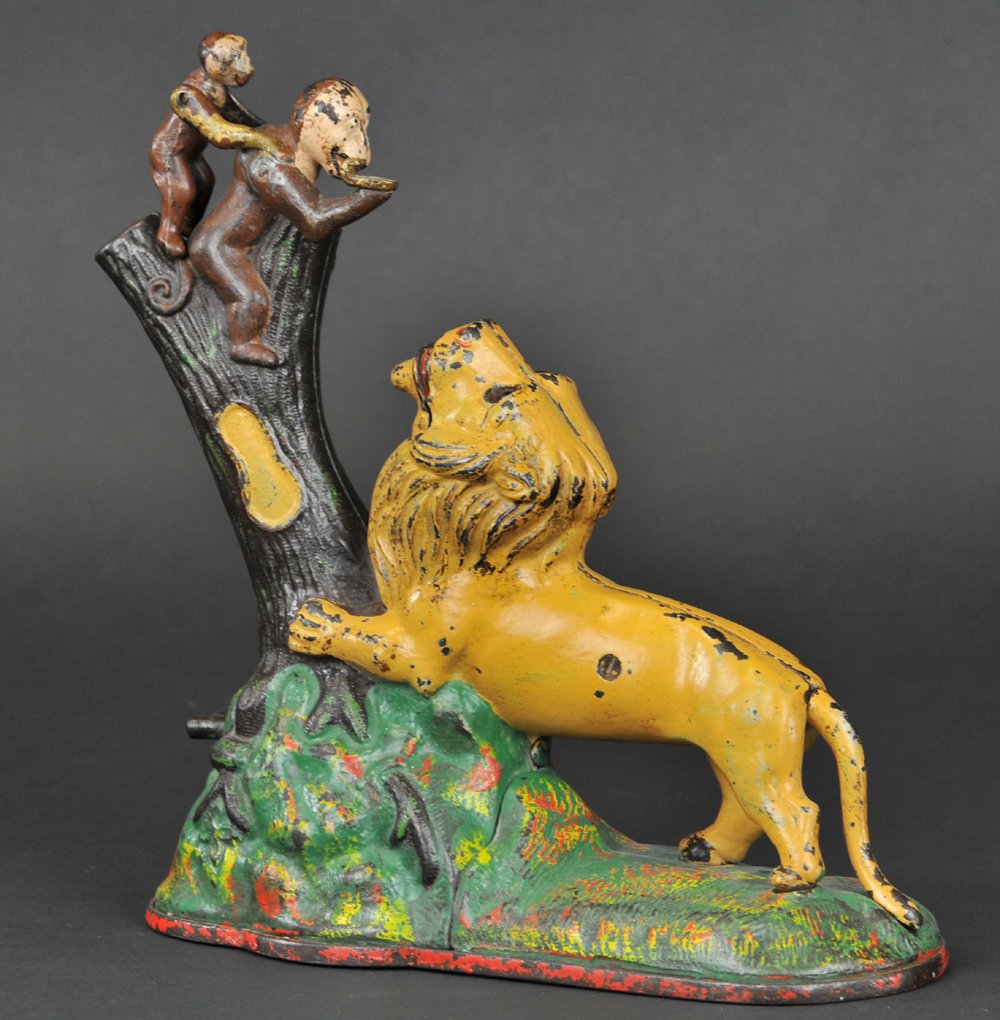 LION & MONKEYS MECHANICAL BANK: Kyser & Rex Co., designed by Louis Kyser & Alfred C. Rex, patented 7/17/1883. “Double Peanut” variety, 8 1/2" tall. Place a coin in the monkey’s hand, and touch a spring at the root of the tree.