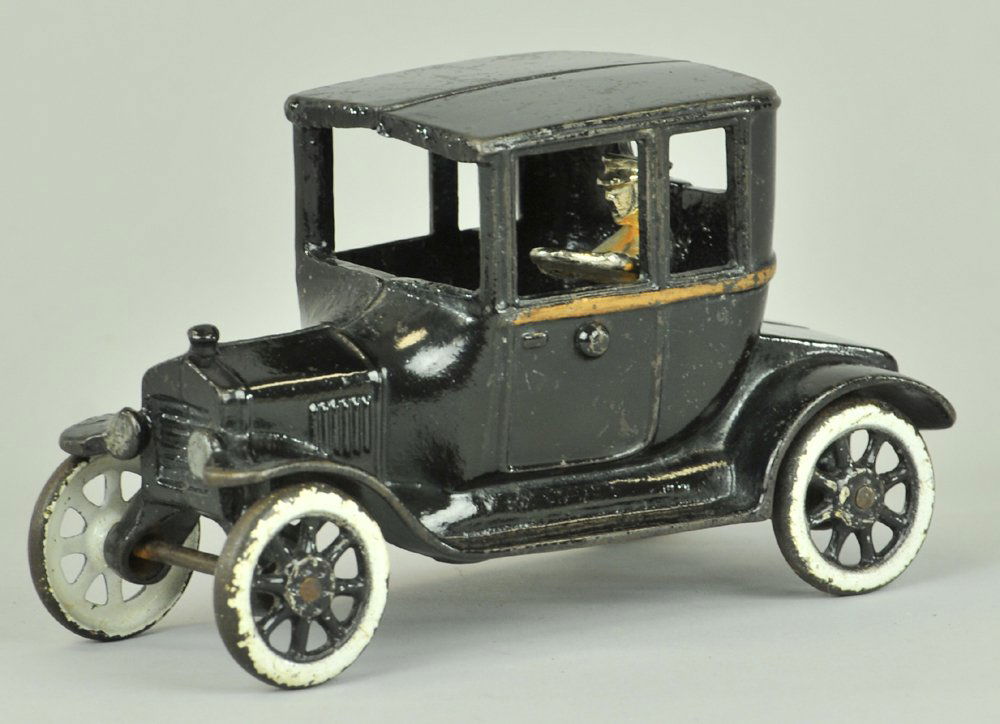 ARCADE FORD MODEL "T" COUPE: Cast iron, painted in black overall, gold striping on side, cast white wall tires, spoke wheels, seated nickel driver. 6 1/2" l.