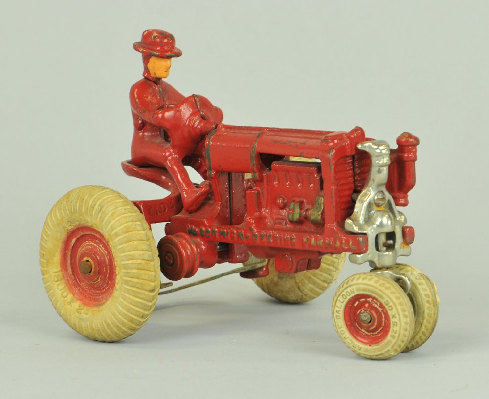 McCORMICK DEERING TRACTOR: Arcade, red painted cast iron Farmall tractor w/driver cast on, nickel plated steering frame, and white rubber tires. 6" l.
