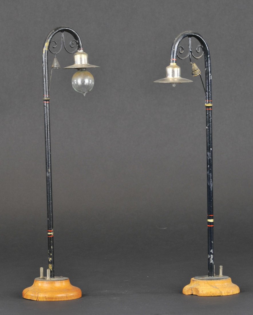 MARKLIN STREET LAMPS: Germany, matching pair, painted in black poles, nickel shades, glass bulb lamps, striping on poles, electric poles on wooden bases. 11 1/2" h.