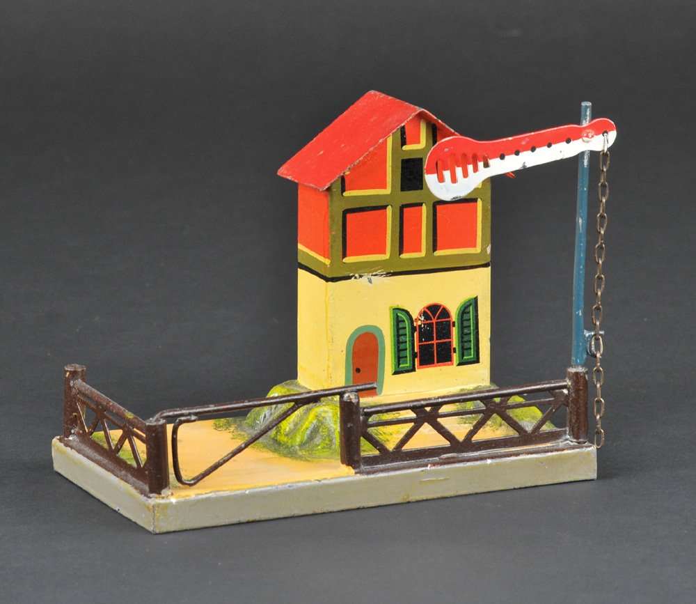 MARKLIN CROSSING GATE: Germany, hand painted tin, crossing gate w/semaphore at one end, gate keeper's house on elevated embossed platform, railed yard, swinging gate, multi-colored example. 5" h.