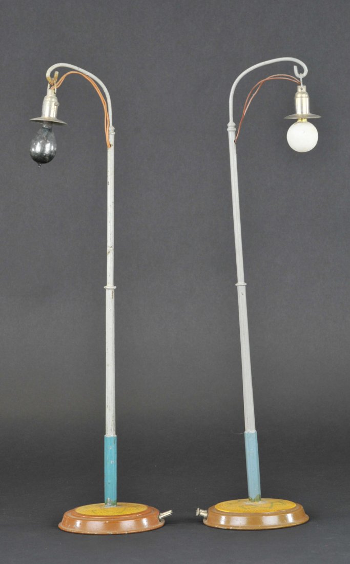 MARKLIN TALL STREET LAMPS: Germany, matching pair, poles painted in grey & blue, lithographed tin circular bases in geometric patterns, nickel shades, both electrified, nice scale. 17" h.