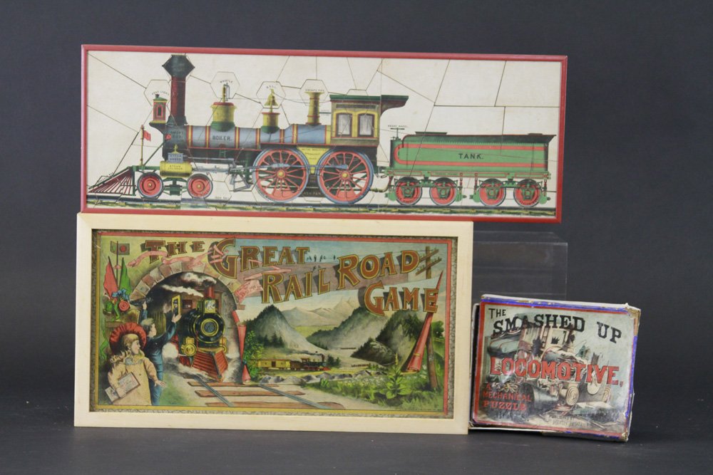 LOT OF TWO EARLY TRAIN ITEMS: Both lithographed paper, features the "Great Railroad Game," and "The Smashed Up Locomotive" puzzle, both nicely framed under glass, strong colors, game complete. 18 1/2" x 23".