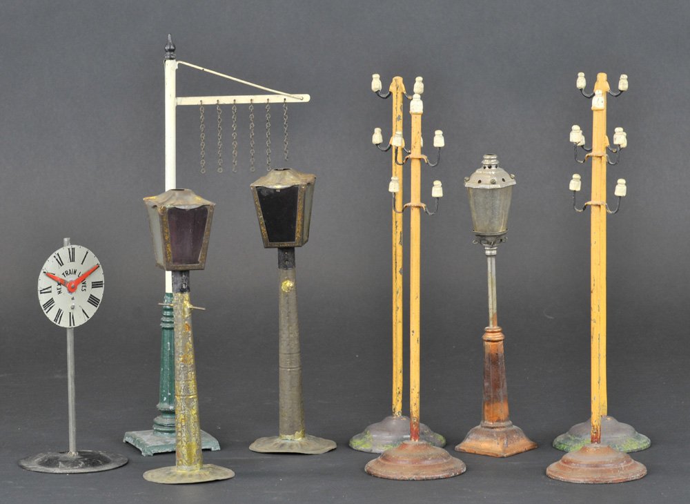 GROUPING OF TRAIN & ACCESSORIES: Lot includes four hand painted Marklin telephone poles with insulators, a non-Marklin height indicator with original chains, train "leaves" tin sign, and three assorted tin lamps, two with wicks, one