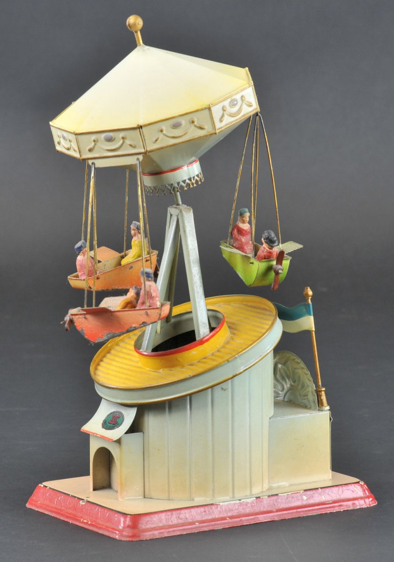 DOLL FLYING CAROUSEL: Germany, c. 1930, desirable example, hand painted, features three airplane rides with seated children, flags appear on entrance roof, very detailed and tilted canopy rooftop, colorful overall. 12 " h.