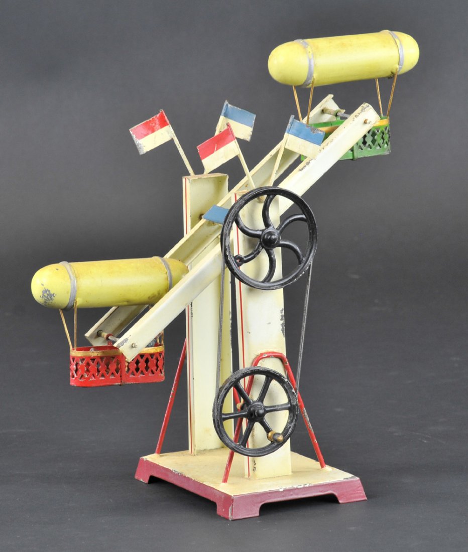 DOLL ZEPPELIN RIDE TOY: Germany, hand painted overall, features two zeppelin rides, each with lower gondolas for seating, hand crank with pulley or as steam accessory. 9" h.