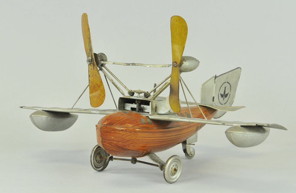 BING SEAPLANE: An early top-mount prop monoplane w/pontoons on wings, fuselage painted in natural wood finish style, clockwork driven, classic toy w/silver wings. 16" wingspan.
