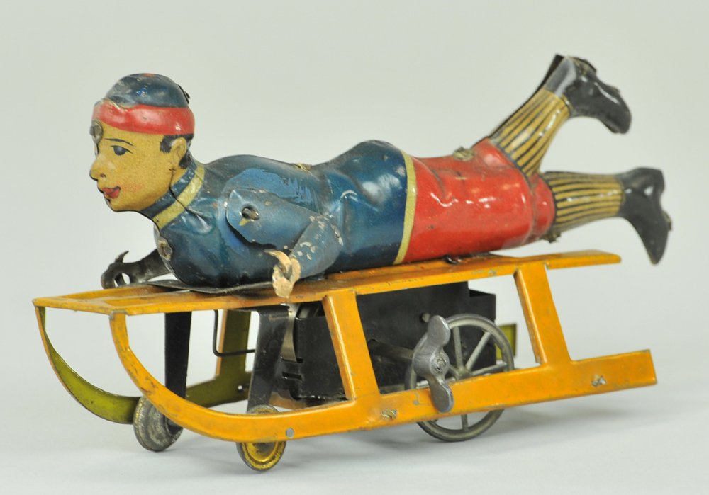 BOY ON SLED TOY: Germany, Hess, lithographed tin, clockwork housed in base, depicted w/legs extended over runners. 6 1/4" l.