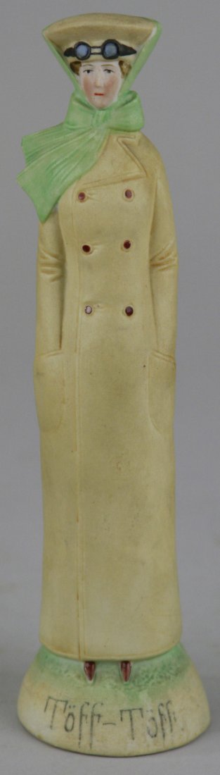 SCHAFER AND VATER FIGURAL: Germany, early Twentieth Century, depicts woman in driving outfit, complete with molded goggles and scarf, base reads, "TÖFF-TÖFF". 7 3/4" h.