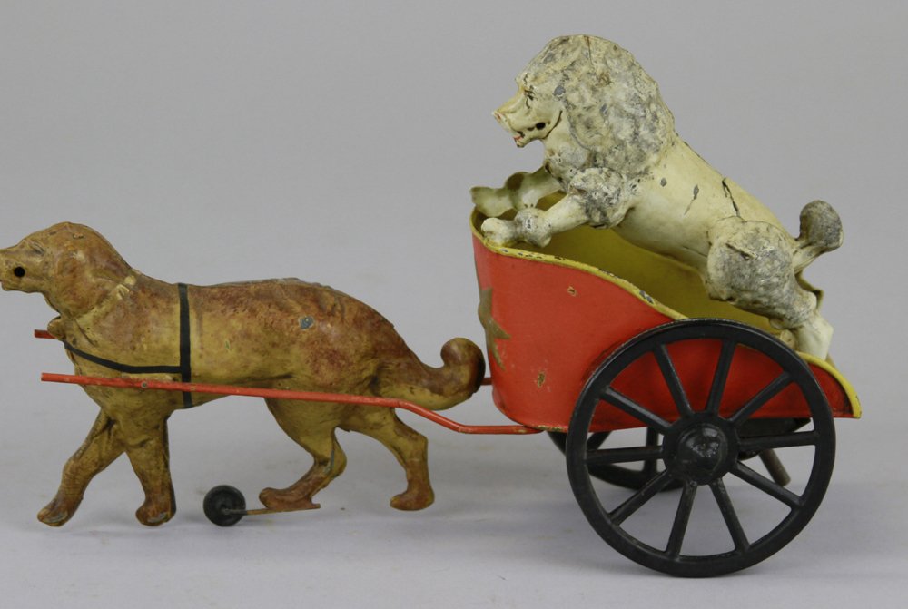 CIRCUS CHARIOT WITH DOG RIDER: Hand painted overall, clockwork driven, depicts poodle standing in chariot drawn by brown dog, spoke wheels, red cart, a great looking toy. 8" l.