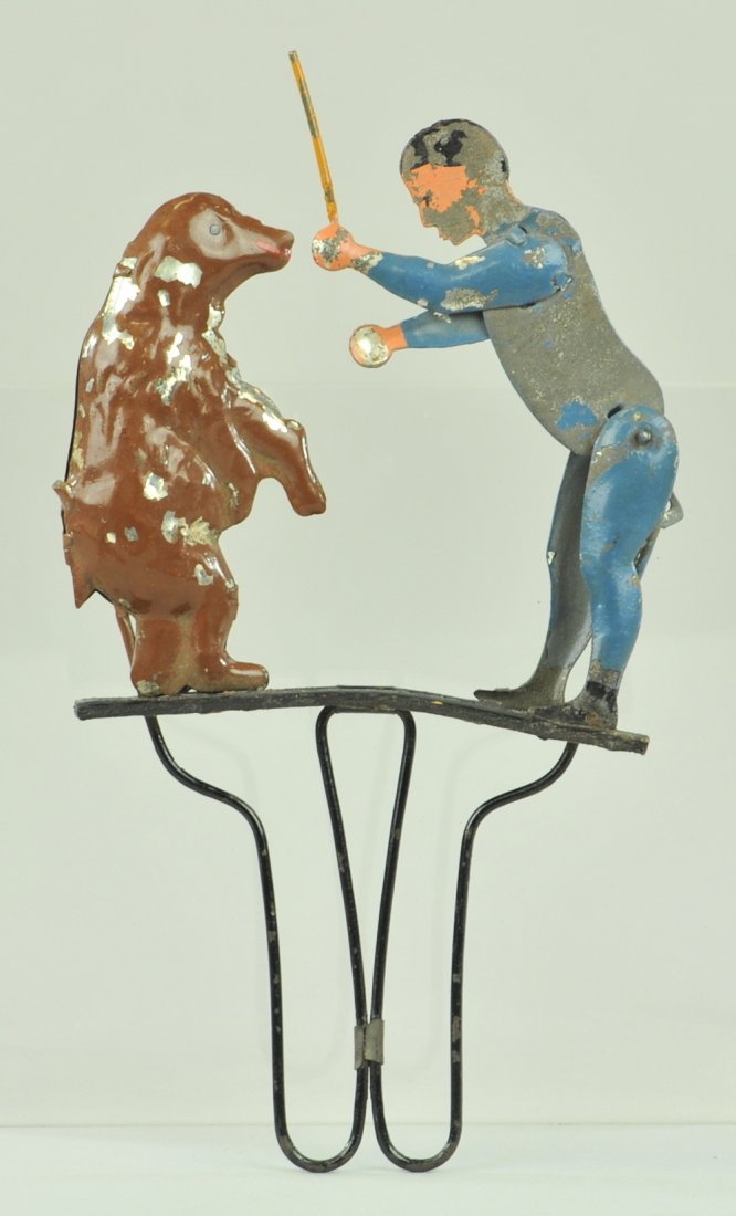 MAN TRAINING BEAR HAND TOY: Scarce example, hand painted tin, squeezing handles creates action, trainer appears to hit bear with stick, attributed to Germany Mfg. 5 1/2" h.