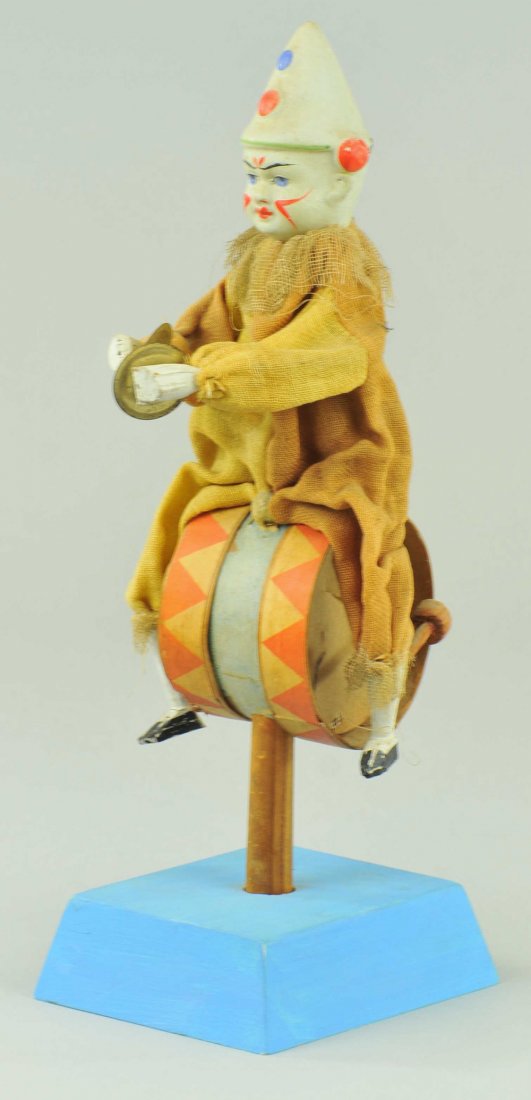 ONE MAN BAND CLOWN TOY: Germany, amusing toy, hand painted composition head clown, able to play cymbals and beat bass drum which he sits on, wears cloth outfit, hand controlled action. 10 1 /4" h.
