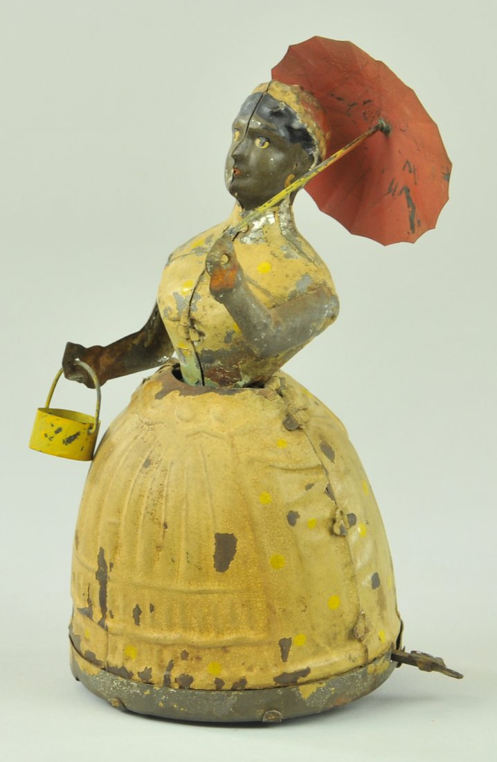 GUNTHERMANN LADY WITH UMBRELLA: Germany, toy was originally known as Aunt Jemima, hand painted tin, depicts lady holding umbrella and tin basket, clockwork driven. 6 1/2" h.
