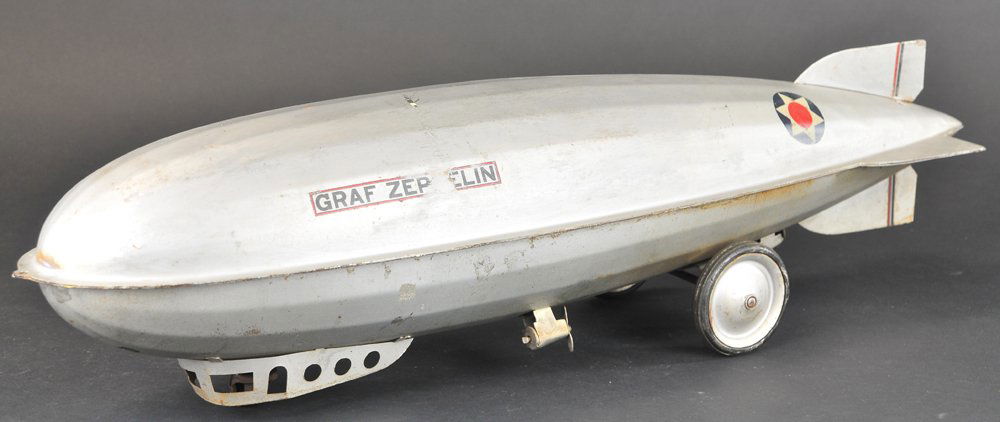 STEELCRAFT "GRAF ZEPPELIN": c. 1930, pressed steel, painted in silver overall, rubber tires, metal discs, features propellers and clicker noise when pulled, complete decals. 25 1/4" l.