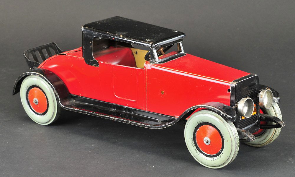 CHEIN HERCULES ROADSTER WITH RUMBLE SEAT: c. 1925, heavy gauge tin, done in red body, black roof and full running boards, simulated headlights, opening rumble seat, large balloon wheels, foldable luggage rack. Ex. Donald Kaufman Collection. 1