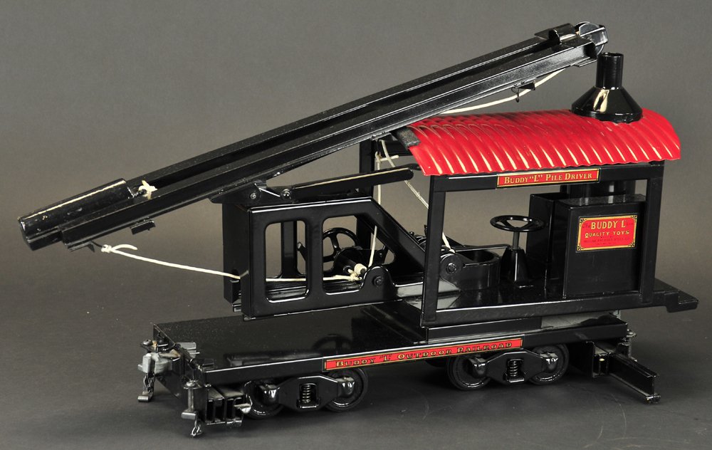 BUDDY 'L' LOCOMOTIVE PILE DRIVER: Contemporary issue, outdoor railroad piece, black housing frame with boiler, red corrugated roof, tall guide rail contains weight, lever controlled, flat car body has four wheel trucks stabilizer exte
