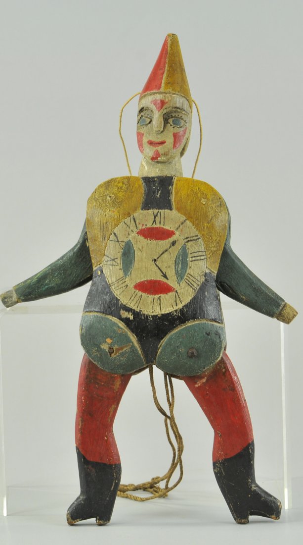 GERMAN CARVED CLOWN JUMPING JACK: Wood jointed body, large clock face painted at center of torso, polychromed in red, blue, and yellow, as string is pulled, clown's arms & legs move up and down, double face example. 13" l.