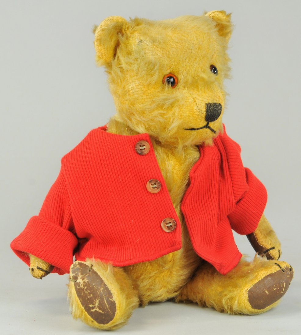 1930's EUROPEAN TEDDY BEAR: Appealing teddy bear in red jacket with stitched nose, plush fur, applied plastic eyes, and leather pads. 13" h.