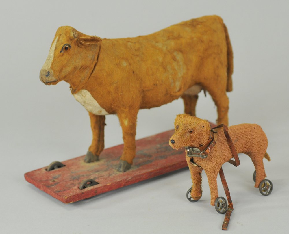 GERMAN COW & DOG PLATFORM TOYS: Early 1900's pull toys, cow has wear to hide, squeaker works faintly, applied glass eyes, and dog with significant hair loss, features original leash & spoke wheels. 4" - 6" l.