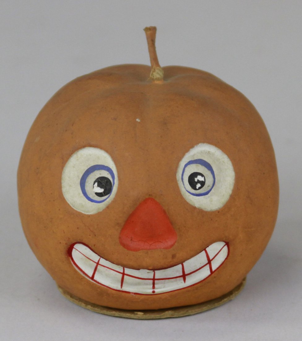 JACK-O-LANTERN CANDY CONTAINER: Germany, composition container done in colorful facial colors, string stem on head, painted orange overall, base removes for candy retrieval. 2 1/2" h.