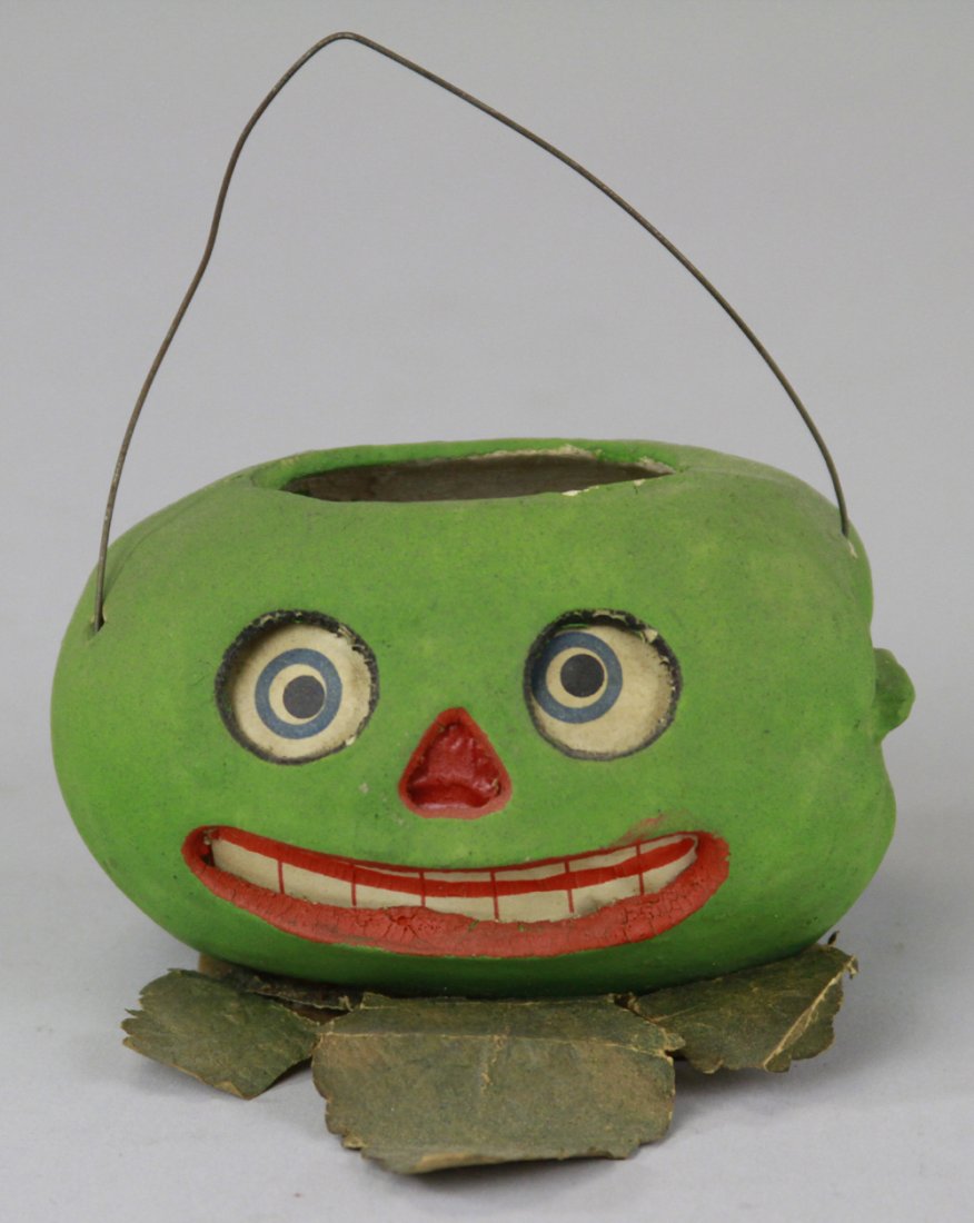 WATERMELON JACK-O-LANTERN CANDY CONTAINER: Germany, composition container done in colorful facial colors, green overall, paper insert for eyes and mouth, wire handle allows easy carry. 2 1/2" h.