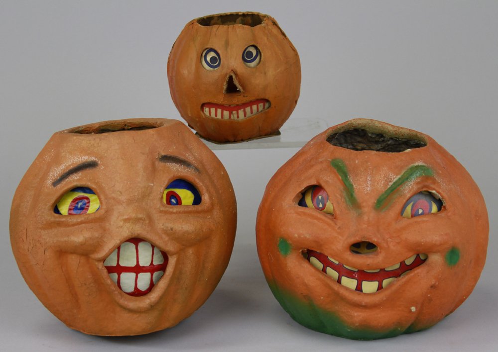 THREE HALLOWEEN JACK-O-LANTERNS: One early German pressed cardboard with extended nose, and two American pulp Jack-O-Lanterns with paper face inserts, all three with wonderful expressions. 5" - 8 1/2".