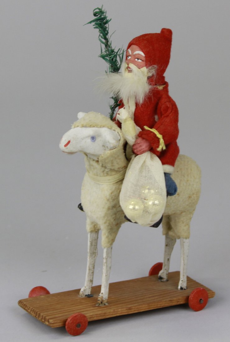 SANTA CANDY CONTAINER ON LAMB: Germany, Santa Claus dressed in red robe, blue pants, rabbit fur beard, holding feather tree sprig, riding on composition head lamb pull toy, charming rendition, Santa's head separates for candy retri