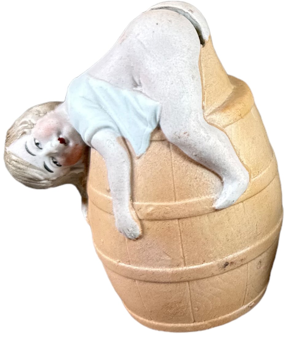 CHILD OVER BARREL STILL BANK: 216. CHILD OVER BARREL STILL BANK | European, ceramic. | Provenance: The John & Adrianne Haley Collection. | 4.5" h. | (Pristine Condition) | $200 - $300