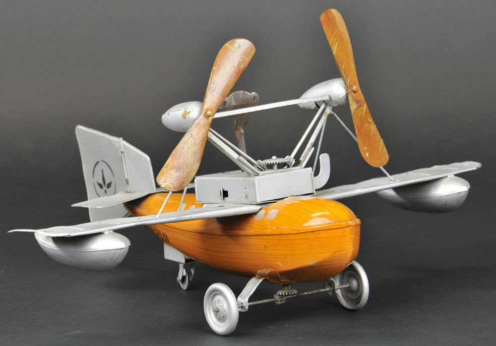 BING SEAPLANE: An early top-mount prop monoplane with pontoons under wings, fuselage painted in natural wood finish, tail fin and wings painted in silver, clockwork driven. 16" wingspan.