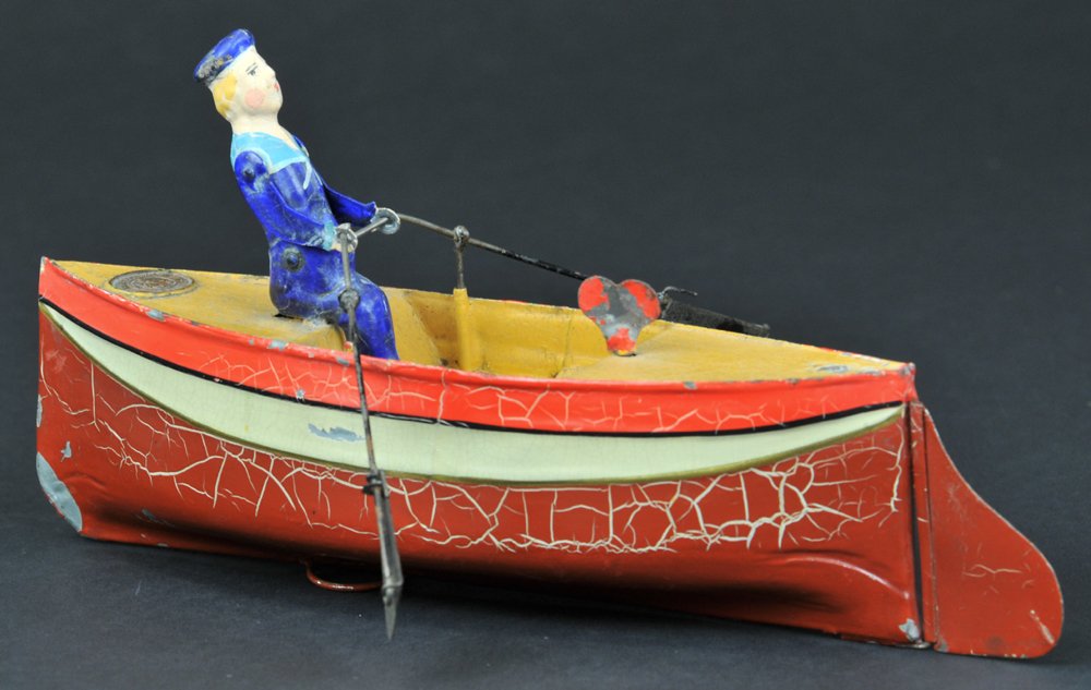ROWER AND ROWBOAT UEBELACKER: Germany, #738/1, circa 1905, hand painted overall, rower has oars in hands, clockwork driven, very colorful hull, once carried small dog at stern. 8" l.