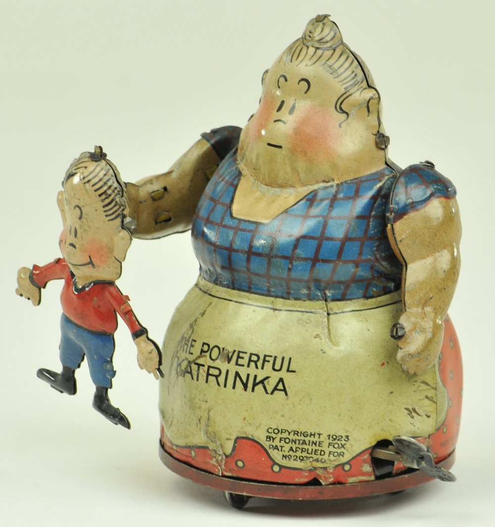 POWERFUL KATRINKA LIFTING JIMMY: Litho tin wind up toy, from Toonerville, the strong lady lifts the boy Jimmy by the back of his shirt, reads "THE POWERFUL KATRINKA, COPYRIGHT 1923, FONTAINE FOX," Geo.Borgfeldt Nifty brand toy, made