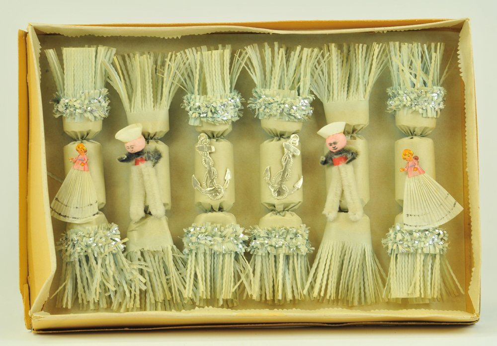 BOXED HOLIDAY CRACKERS: Unique box of six ornate snapping crackers with paper die-cut images on composition head, sailors at center, very colorful, very different. Each 9" l.