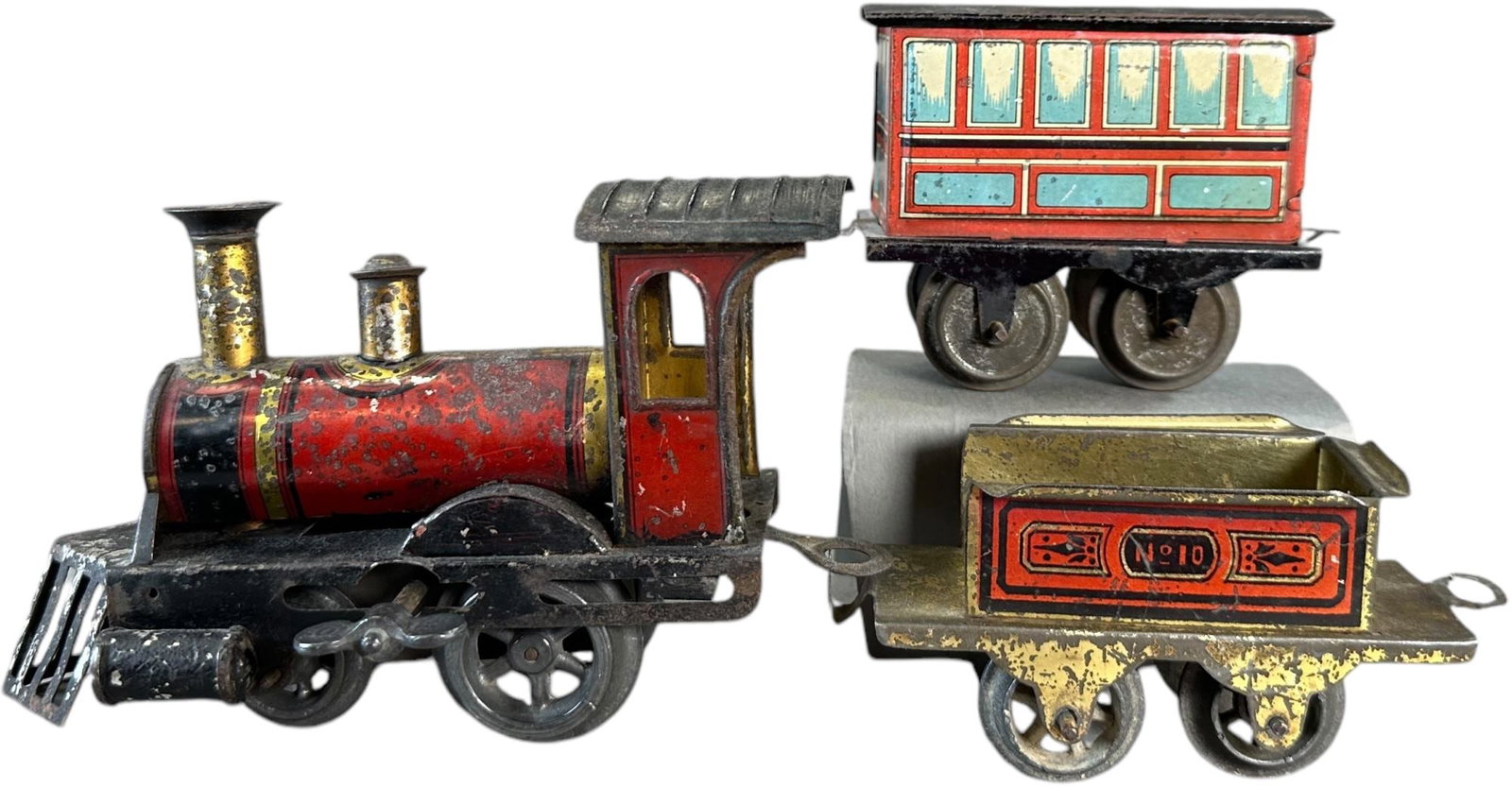 ISSMAYER AMERICAN STYLE LOCO W/ ELABORATE TENDER: 365. ISSMAYER AMERICAN STYLE LOCO W/ ELABORATE TENDER | O gauge, wind-up 2-2-0 loco with elaborate ornate tender and red litho coach. Ex: Bill Becker Collection. | 5.5" l. | Loco (Very Good Condition)