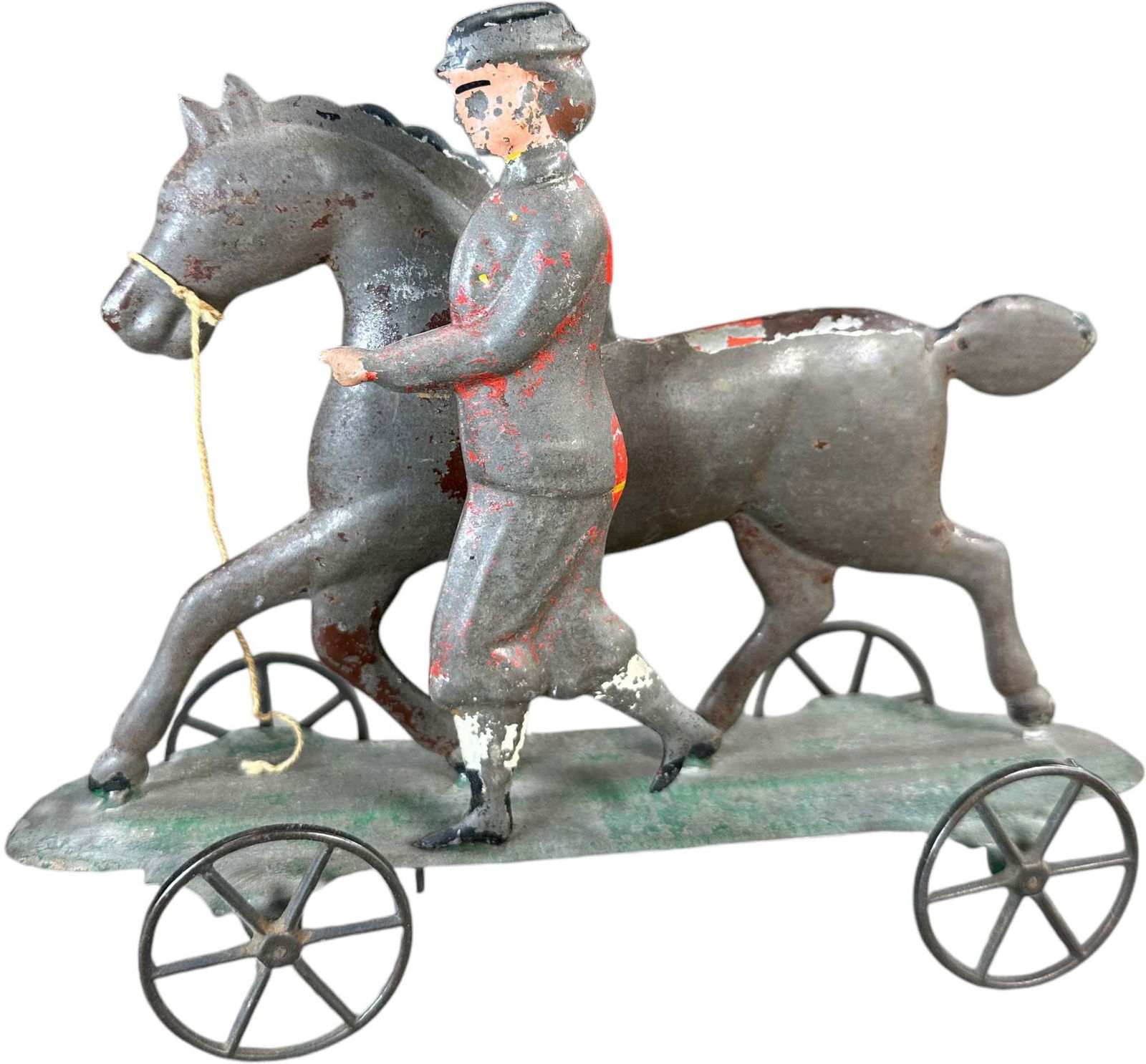 AMERICAN TIN HORSE TRAINER PULL TOY: 421. AMERICAN TIN HORSE TRAINER PULL TOY | The epitome of fabulous early Americana toy form. | 9" l. | Paint is original but worn, (Very Good Condition) | $350 - $700