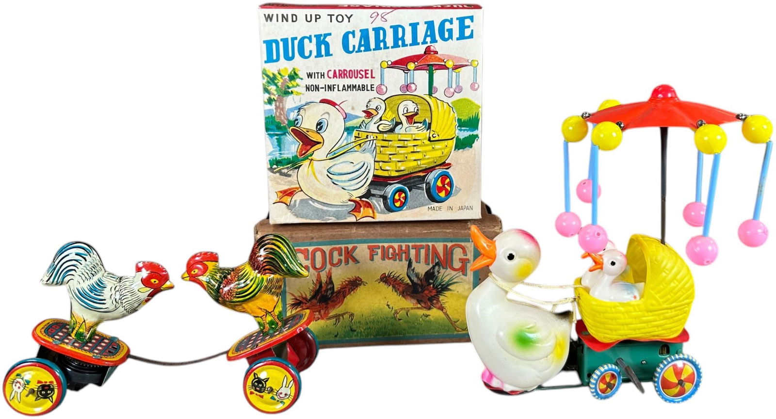 TWO BOXED JAPANESE WIND-UP TOYS: 276. TWO BOXED JAPANESE WIND-UP TOYS | Japan, wind-up motors. Fighting chickens toy and wind-up celluloid toy with spinning parasol. | 6" l. | Cock fight has some minor tears to lid flaps, (Excellent