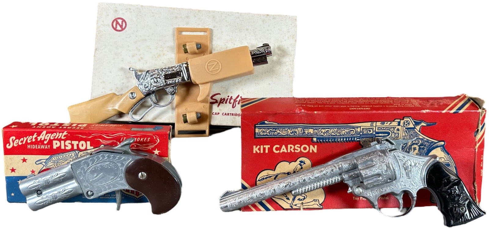 THREE BOXED WESTERN CAP GUNS: 460. THREE BOXED WESTERN CAP GUNS | Lot includes: Boxed Carson's, spitfire, and secret agent. | 9.5" l. | Overall (Excellent to Pristine Condition) | $100 - $200