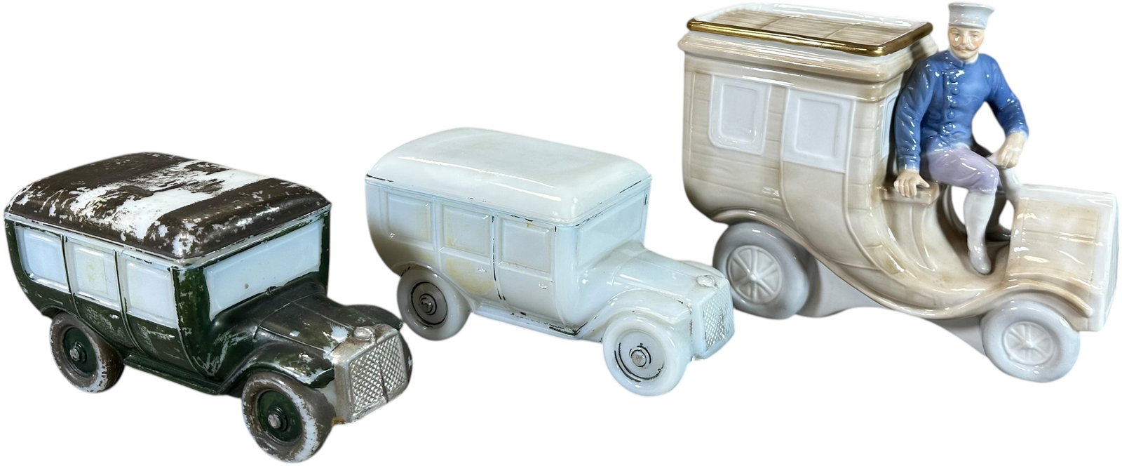 TWO MILK GLASS CIGARETTE HOLDERS & COIN BANK: 164. TWO MILK GLASS CIGARETTE HOLDERS & COIN BANK | From the David Bausch Automobilia collection. | 8" l. | Paint worn off on one milk glass container, tape residue and two glued cracks on green car (