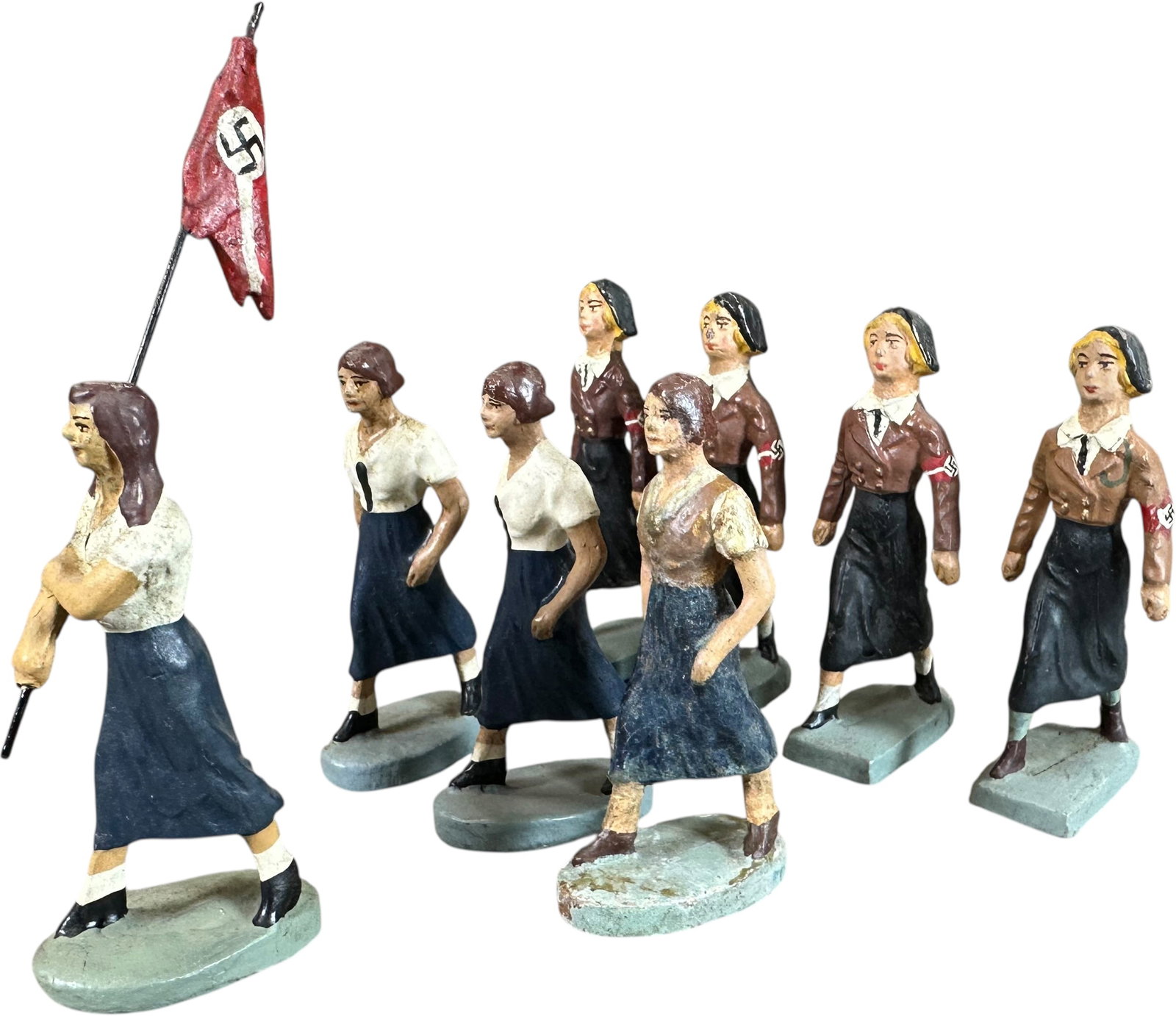 GERMAN COMPOSITION BDM FIGURES: 222. GERMAN COMPOSITION BDM FIGURES | Eight BDM (Bunde Deutches Madel) or girls Hitler Youth, includes four Lineol and four Elastolin, one of which extremely rare girl carrying a party pennant. From t