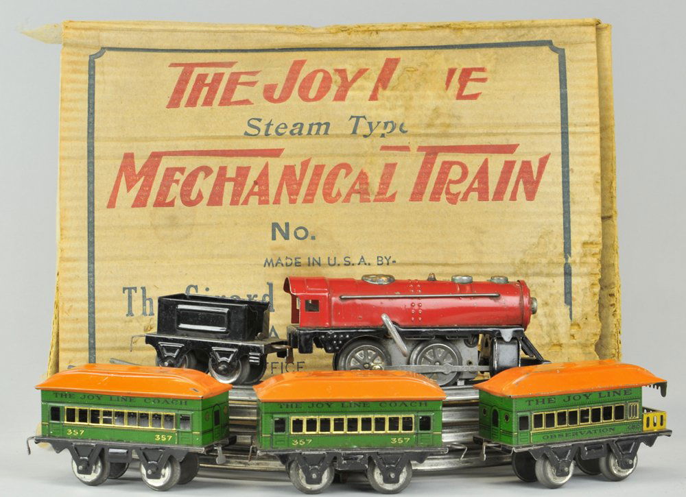 GIRARD MECHANICAL TRAIN SET: Box example, contains wind-up red locomotive with black tender, together with three "Joy Line," passenger cars in green bodies and orange roofs, includes track. Loco 7", cars 4 1/2".