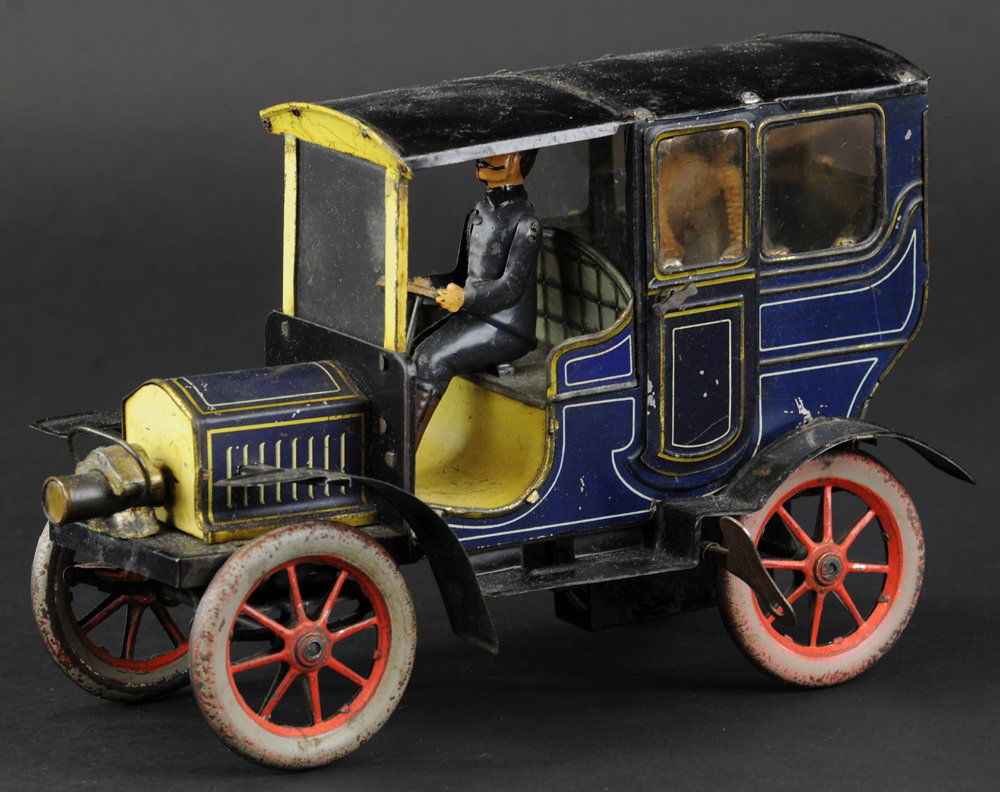 CARETTE LIMOUSINE: Germany, c. 1919, lithographed tin, done in blue overall, gold striping, seated passenger figure, head lamp, unique solo head lamp at front, clockwork driven. 9 1/2" l.