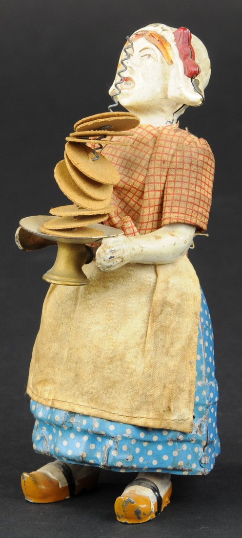DUTCH GIRL BALANCING PLATES: Martin, France, hand painted figure of Dutch girl with stack of plates in hand, clockwork controls ejection of all plates, quite amusing. 6 1/2" h.