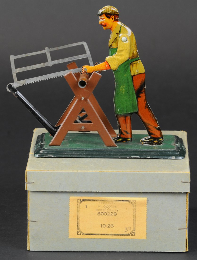 BOXED BING MAN SAWING STEAM ACCESSORY TOY: Germany, lithographed tin, hand cranked or connected to steam engine by pulley, log on trestle, saw in man's hands. 6" l.