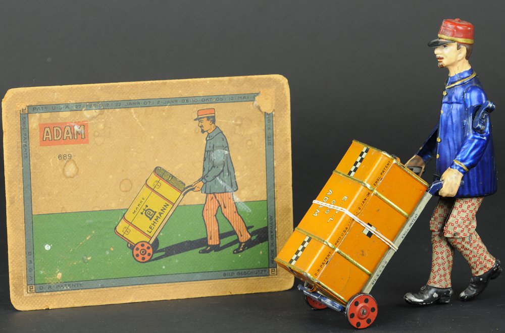 LEHMANN ADAM THE PORTER WITH BOX LID: Germany, hand painted and lithographed tin, curious toy depicts porter pushing hand car with suitcase, clockwork driven, another every day job turned into a playful toy. 8" h.