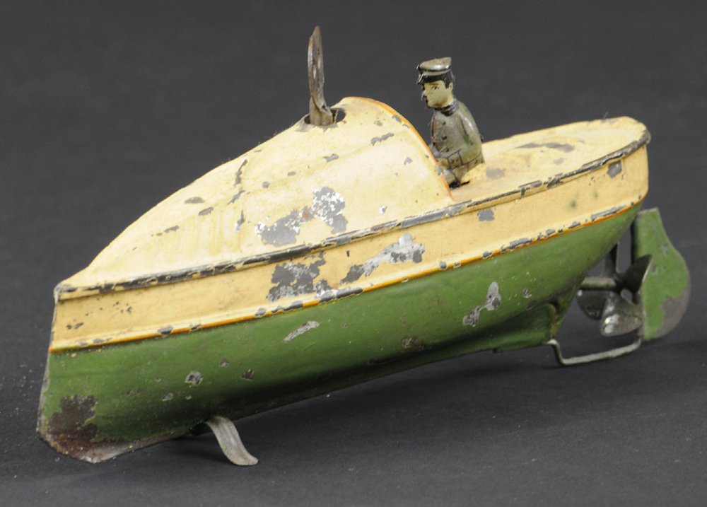 CARETTE SPEEDBOAT: Germany, hand painted tin, done in cream and green, features clockwork drive and seated pilot. 6 3/4" l.