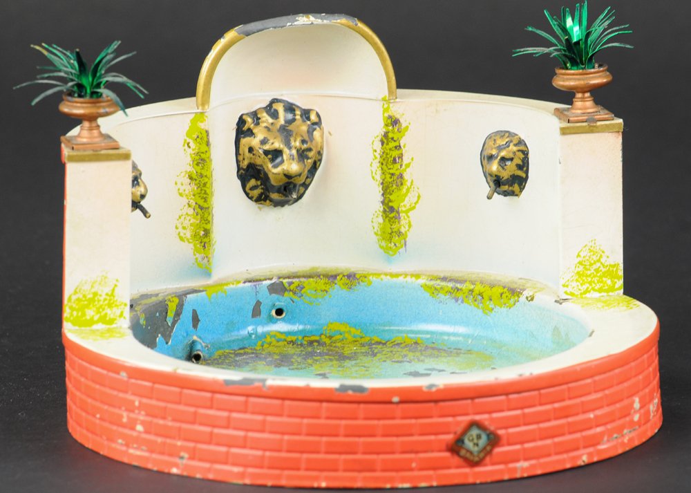 BING FOUNTAIN: Germany, hand painted steam accessory toy, features lion head spigots, hand or steam propelled crank at rear, embossed brickwork patterned circular base. 7 3/4" diam.