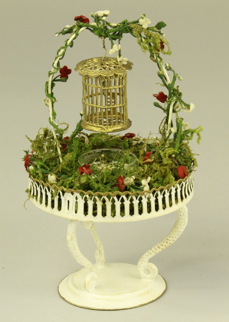 ROCK & GRANER BIRD BATH: Germany, very intricate tin plate example, features detailed circular railing, glass water bowl at center, and bird cage hanging from elaborated decorated handle. 7" h. x 4" diam.