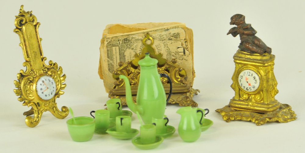MINIATURE ACCESSORY GROUPING: Includes an ormolu barometer, ormolu newspaper holder, rare ormolu clock with cupid on top, and a green glass opulent tea set. Barometer 2 5/8" h.